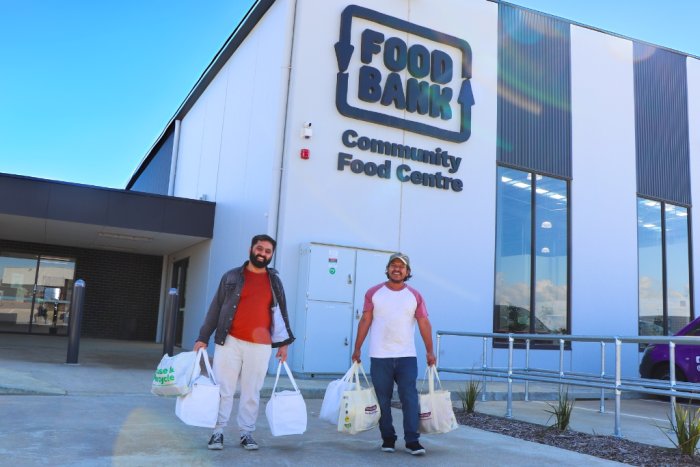 Two male students leaving the Foodbank Community Food Centre with bags full of food